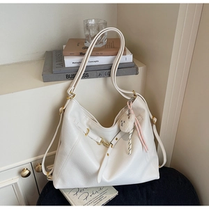 Detail of off-white lychee texture tote bag with golden buckle and plush bear charm