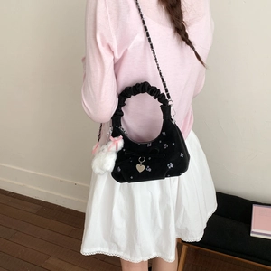 Détail du sac hobo en velours noir avec broderies florales, nœud et charm lapin peluche