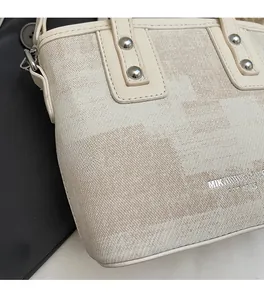 Détail d'un sac cabas en tissu beige avec motifs géométriques et clous argentés