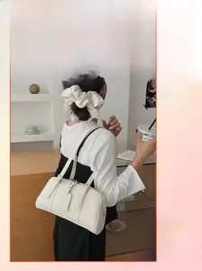 Detailed view of cream white pillow shoulder bag featuring adjustable leather straps and metal buckles