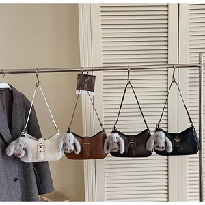 Detail view of four minimalist hobo bags in assorted colors with plush bunny charms