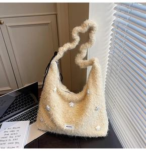 Detail of beige faux fur tote bag featuring wavy straps and star patches on a desk