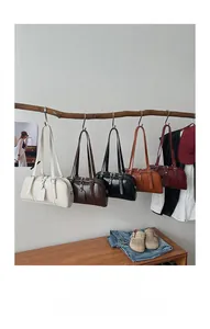 Detail view of leather Boston bags in five colors hanging on wooden branch decor