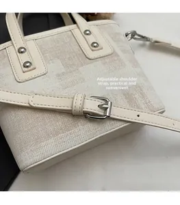 Détail de la bandoulière réglable avec boucle en argent sur le sac seau en toile beige