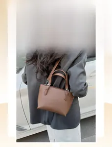 Close-up of brown litchi pattern leather texture and metal buckle detail on bucket bag