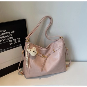 Detail of pink faux leather tote bag with metal buckle and cute white bear keychain