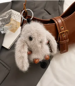 Detail of a plush bunny charm with leather limbs on a brown designer shoulder bag