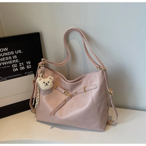 Detailed view of pink PU leather tote with golden buckle and cute plush bear charm