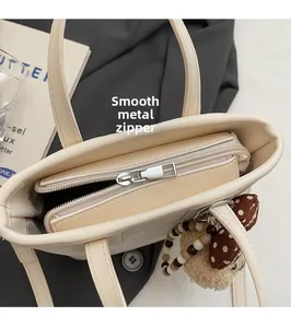 Vue de dessus du sac seau beige montrant le compartiment zippé et la ferrure dorée