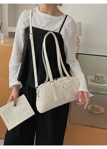 Close-up of cream Boston bag with metallic adjustable buckle and stylish strap details