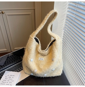 Detail of beige fuzzy tote bag featuring plush stars and aesthetic lace brand label