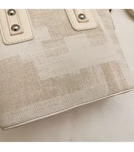 Gros plan sur la texture géométrique du tissu et les rivets de ce sac seau beige chic