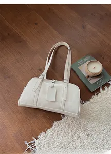 Detail view of a cream white glossy patent leather Boston bag on a cozy textured rug
