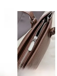 Detailed close-up of smooth silver zipper hardware on brown pebble grain bucket bag