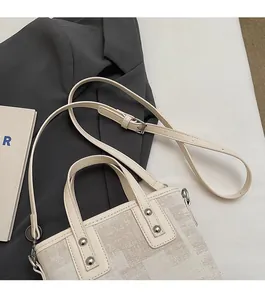 Détail de la bandoulière réglable et rivets argentés sur le sac seau crème élégant