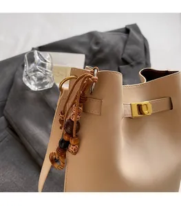 Detail of beige leather bucket bag with multi-color wooden bead pendant and gold hardware