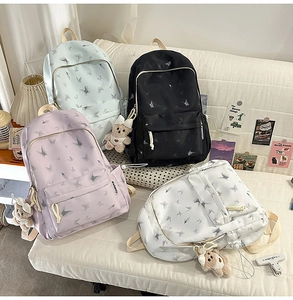 Detail of four colorful nylon school bags with butterfly prints and teddy bear charms
