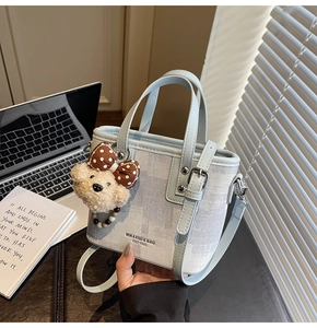 Détail du mini sac seau en toile avec poignées en cuir et porte-clé ourson mignon
