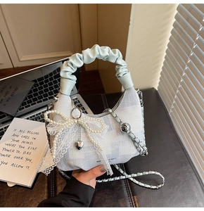 Detail of light blue checkered dumpling bag with pearl lace bow and heart pendant