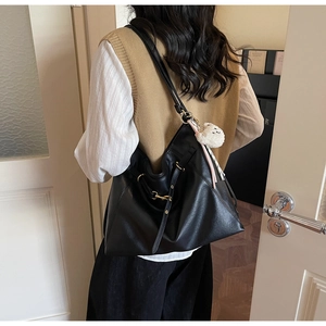 Detail of black faux leather tote with soft texture and white plush animal charm