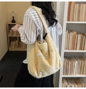 Detail of yellow fuzzy tote bag with star patch and soft plush texture on strap