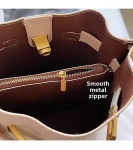 Detail of golden metal swivel lock and smooth zipper inside beige bucket bag
