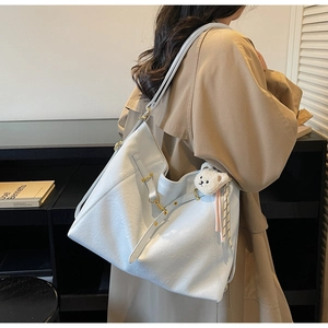 Detailed view of blue faux leather tote with golden buckles and cute white bear charm