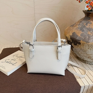 Detail view of cream bucket bag with lychee texture, metal buckles and silver zipper