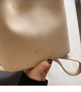 Detailed macro view of beige leather texture with gold logo and red nail hand model