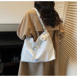 Detail of light blue leather tote bag with plush bear charm and gold hardware accents
