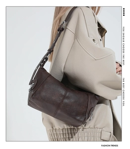 Detail of a dark brown retro leather shoulder bag with textured finish and silver hardware
