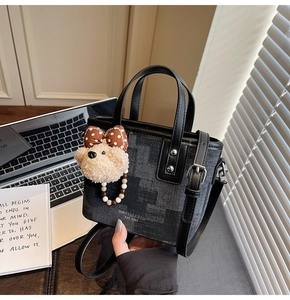 Détail du sac seau bandoulière avec texte de marque et breloque ours en peluche