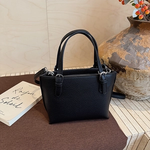 Detail of black pebbled leather bucket bag with silver rings and detachable shoulder strap