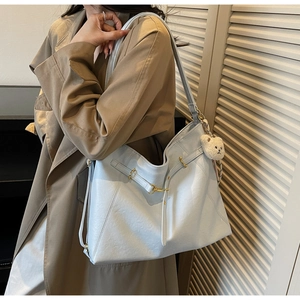 Detail of light blue hobo tote bag with golden buckle and cute plush bear charm