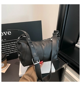 Detail of black dumpling bag showing lychee leather texture and silver metal eyelet strap