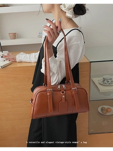 Detail of a brown PU leather shoulder bag featuring dual zippers and long handles
