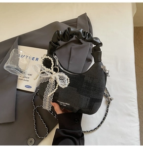 Detailed texture of dark grey jacquard crescent bag with lace bow and pearl chain details