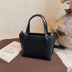 Close-up of black lychee grain leather bucket bag with silver buckle and crossbody strap