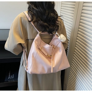 Detail of light pink faux leather tote bag with gold metal buckles and plush bear charm
