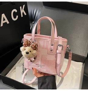 Détail d'un sac seau rose avec texture dégradée et breloque ours en peluche