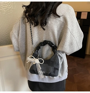 Detail showing grey plaid dumpling bag with white lace bow and faux pearl decoration