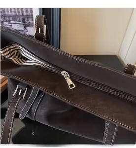 Detail of vintage brown tote bag with smooth metal zipper and striped inner lining