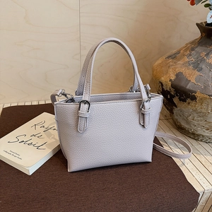 Detail of light purple litchi grain leather bucket bag with metallic hardware and strap