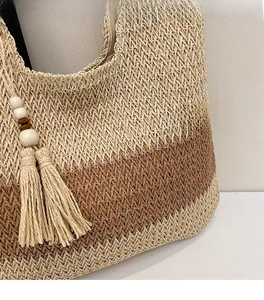 Detail of the dual-color woven straw tote bag with V-shaped patterns and tassel charm