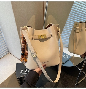 Detail of cream bucket bag showing gold metal clasp and retro wooden bead charm