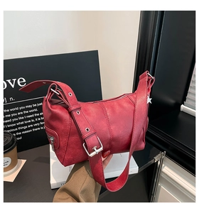 Detail view of retro red leather shoulder bag with wide strap and silver buckle