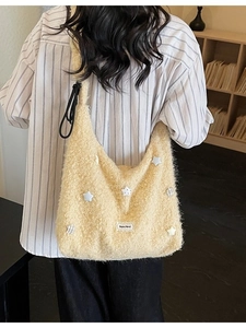 Large fluffy beige hobo bag with colorful star patches and adjustable strap shown on model