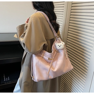 Detail of light pink faux leather tote bag with gold buckle and cute bear charm