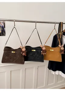 Détail de sacs cabas rétro en marron, noir et beige avec boucles dorées et ours en peluche