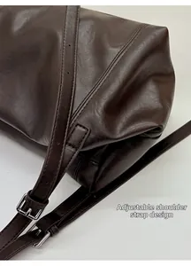 Detail view of the adjustable shoulder strap with silver buckle on dark brown tote bag